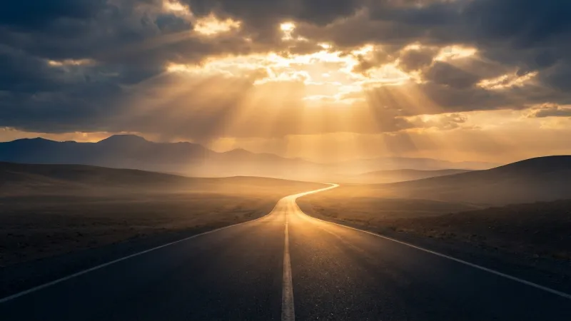 夕日に照らされた一本道が遠くまで続く風景