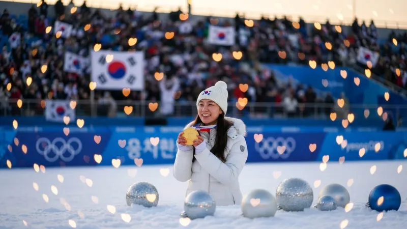 観客席の国旗と温かいハートの光に包まれて金メダルを掲げるシーン