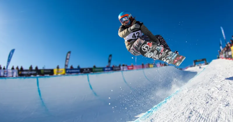 ハーフパイプでジャンプする女性スノーボーダー